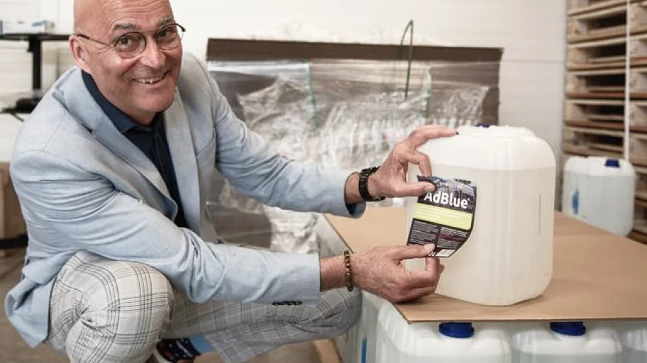 Cyrill Hugi, CEO of the enespa Group, kneels in front of a pallet of plastic containers. They contain freshly produced AdBlue, ready to be dispatched by lorry.