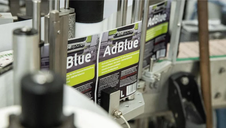 Die Kunststoffbehälter mit AdBlue werden auf einem Förderband automatisch mit Etiketten beklebt.